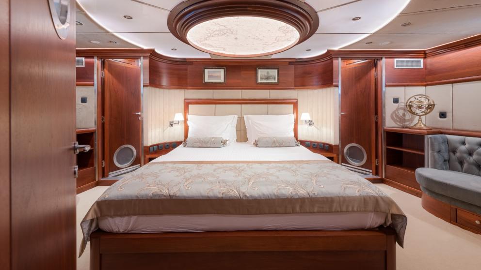 Ein dezent dekoriertes, bequemes Doppelbett steht unter der runden Luxus Glaslampe in der Master Kabine.